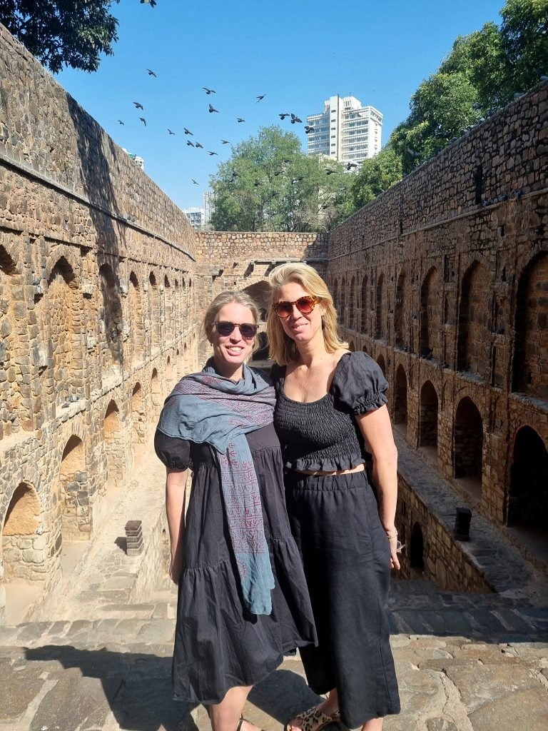 Two foreign girls posing at Agrasen ki Baoli, a stepwell in Delhi, India. They are on a food and photography walking tour and are enjoying the beauty of the baoli. Agrasen ki Baoli is one of the oldest and largest stepwells in Delhi.